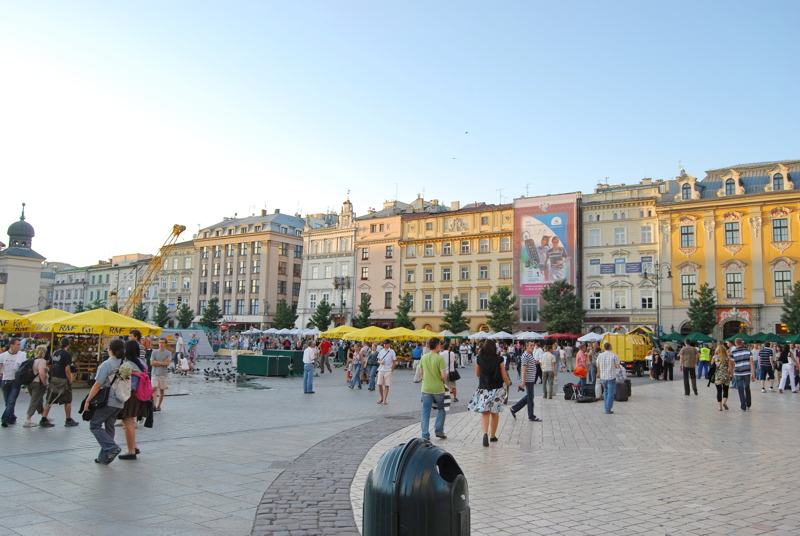 12 - The vibrant Rynek Główny (Main Square) in Kraków, Poland, featuring historic townhouses, market stalls, and pedestrians under a clear sky